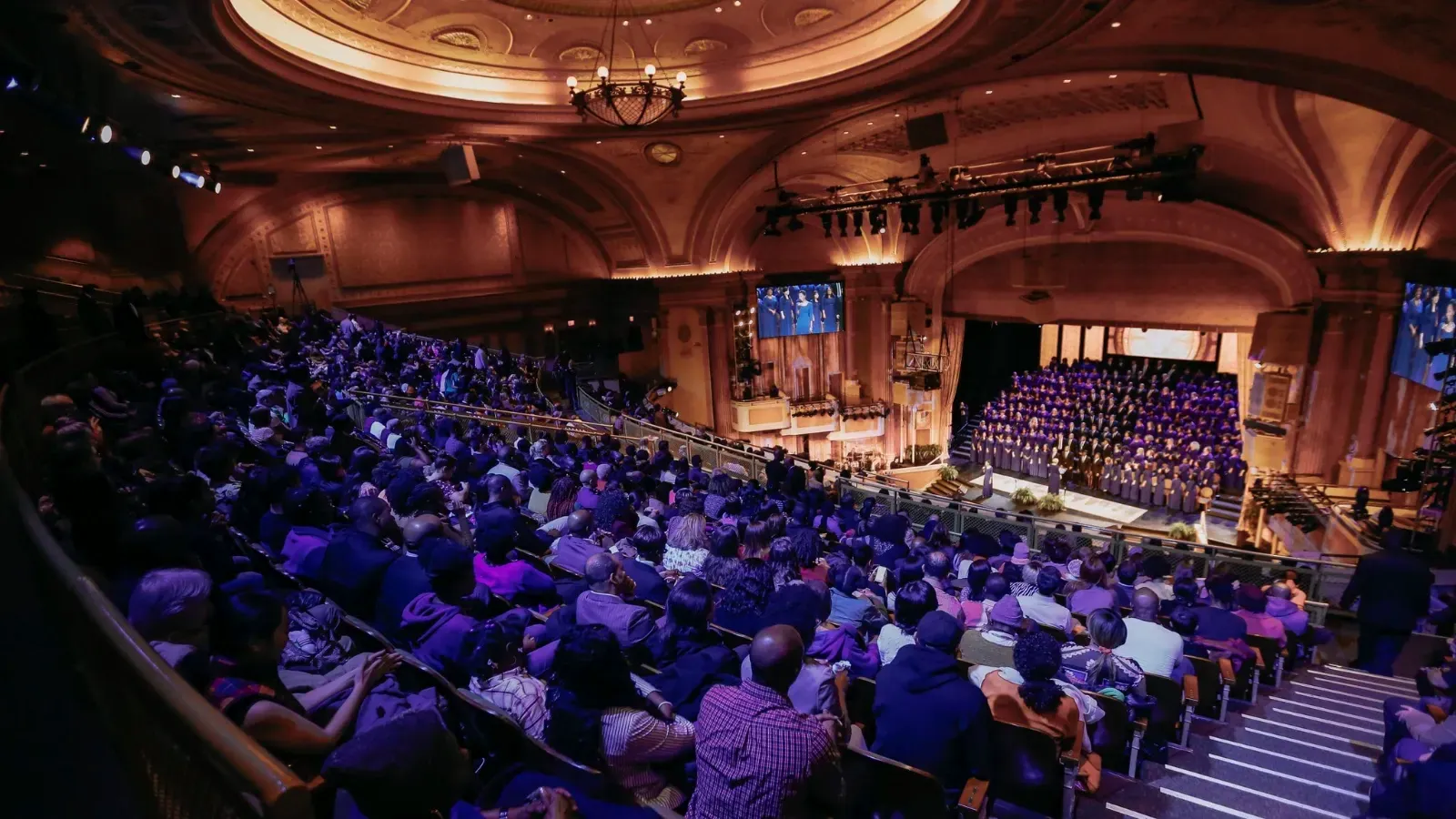 Brooklyn Tabernacle seen from the balcony, the auditorium full under a domed ceiling and the choir massed in purple robes on the stage
