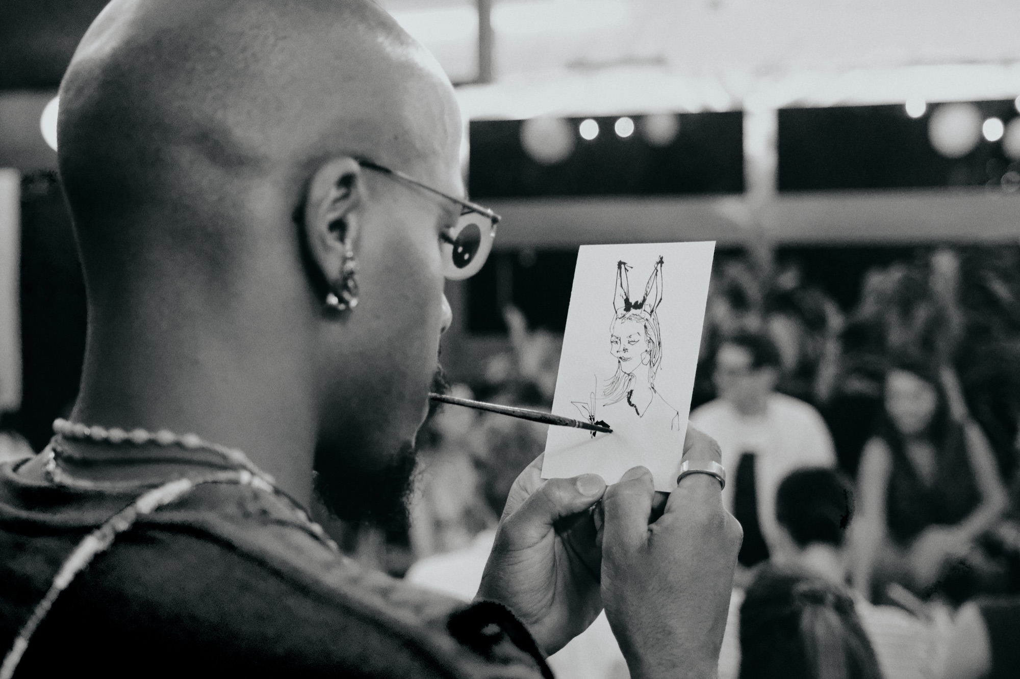 Dig Ferreira in profile drawing with a Japanese sumi brush held in his mouth